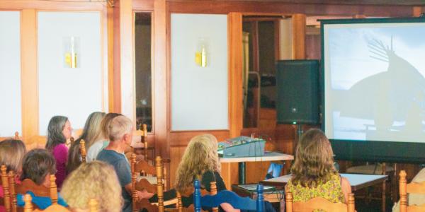 The audience watches the film "Falls Around Her" by Darlene Naponse at Hotel Wolfe Island.