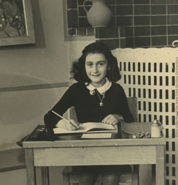old picture of anne frank at desk with diary