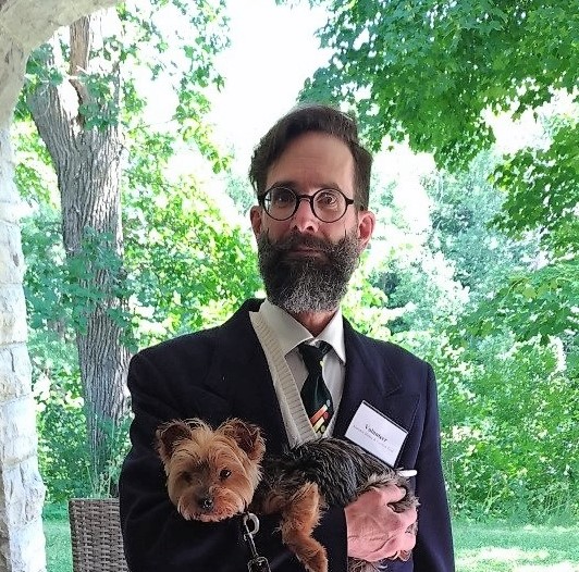 Paul in blazer, tie holding puppy