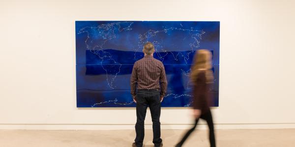 Man in front of blue landscape art with woman movement
